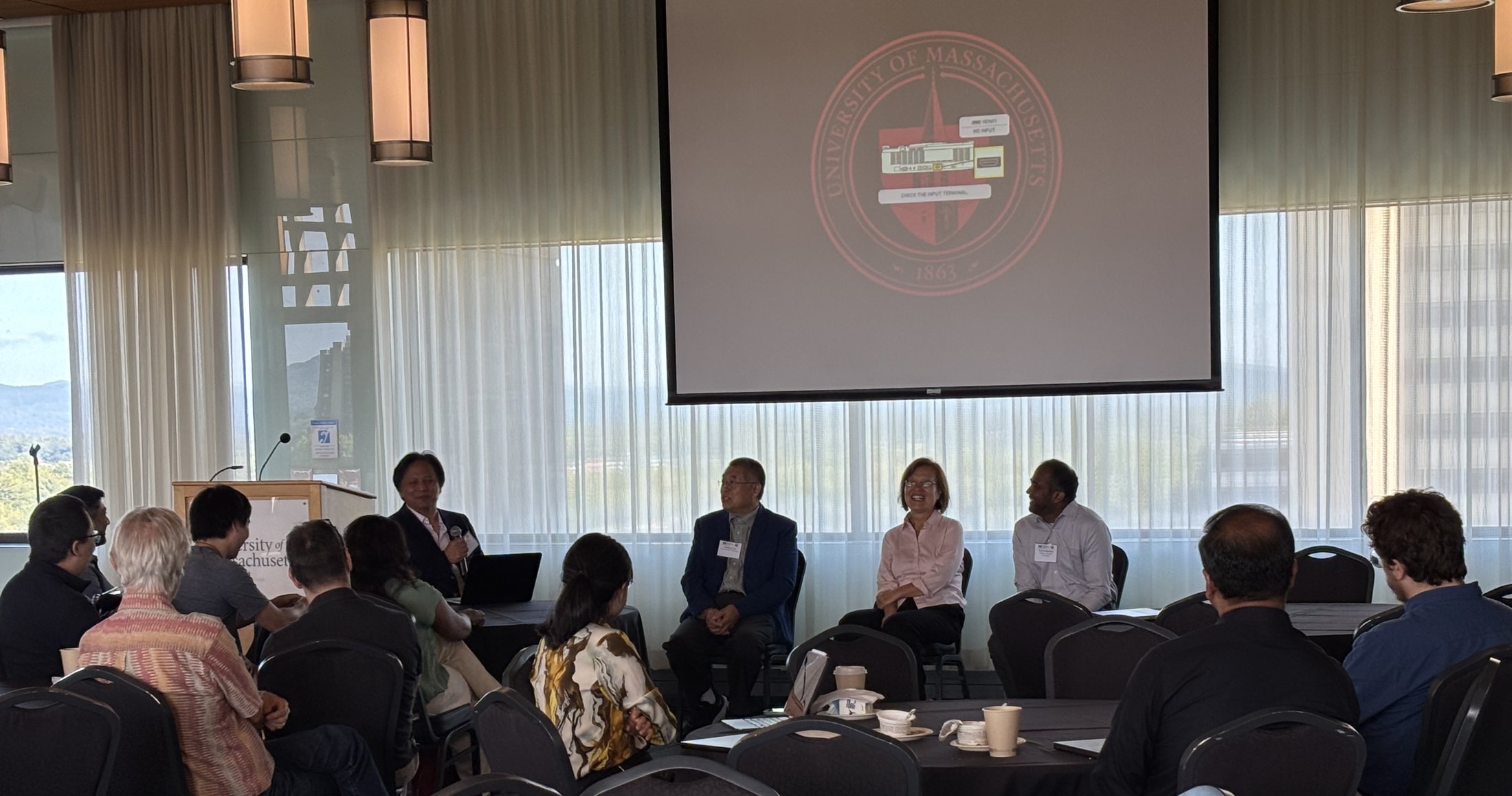 Four speakers seated at the front of the room during a panel discussion.